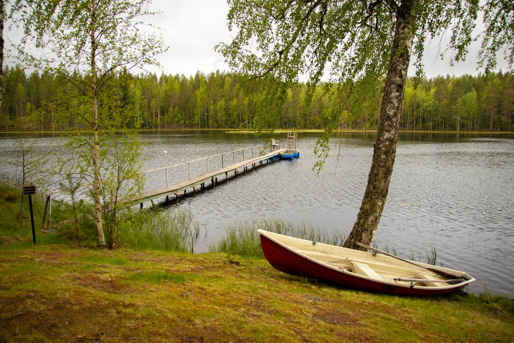 Pitkä laituri, jonka päässä hyppytorni ja penkki. Rannassa myös soutuvene.