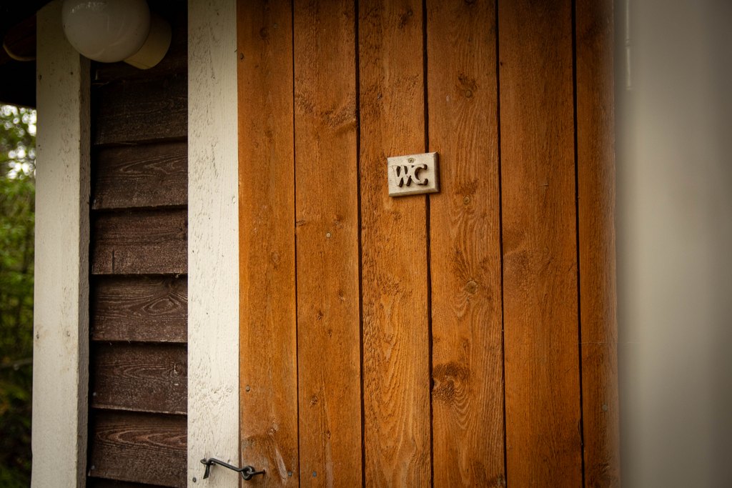Huussin ovi, jossa kyltti "WC".