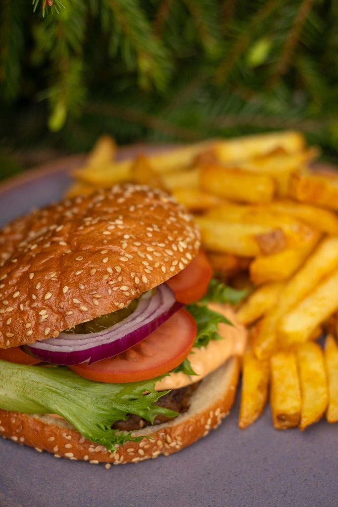 Hampurilainen, jonka välissä jauhelihapihvi ja salaattivermeet. Vieressä lisäksi ostettavat ranskalaiset.