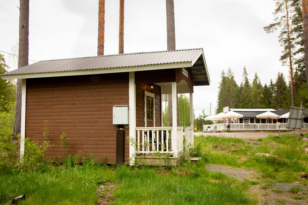 Portinvartijat 1, 2 ja 3 Pieni, jopa piparkakkutalomainen mökki kuvattuna ulkoa. Taustalla kauempana näkyy ravintola.
