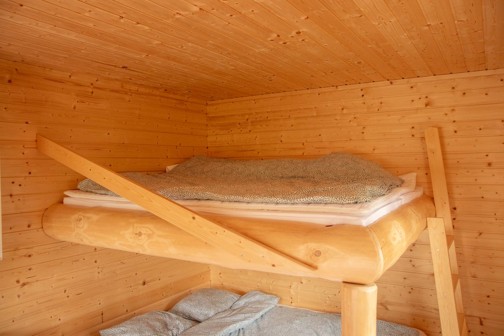 Portinvartijat 1, 2 ja 3 Kelopuista rakennettu leveä kerrossänky, jossa sinertävät lakanat.